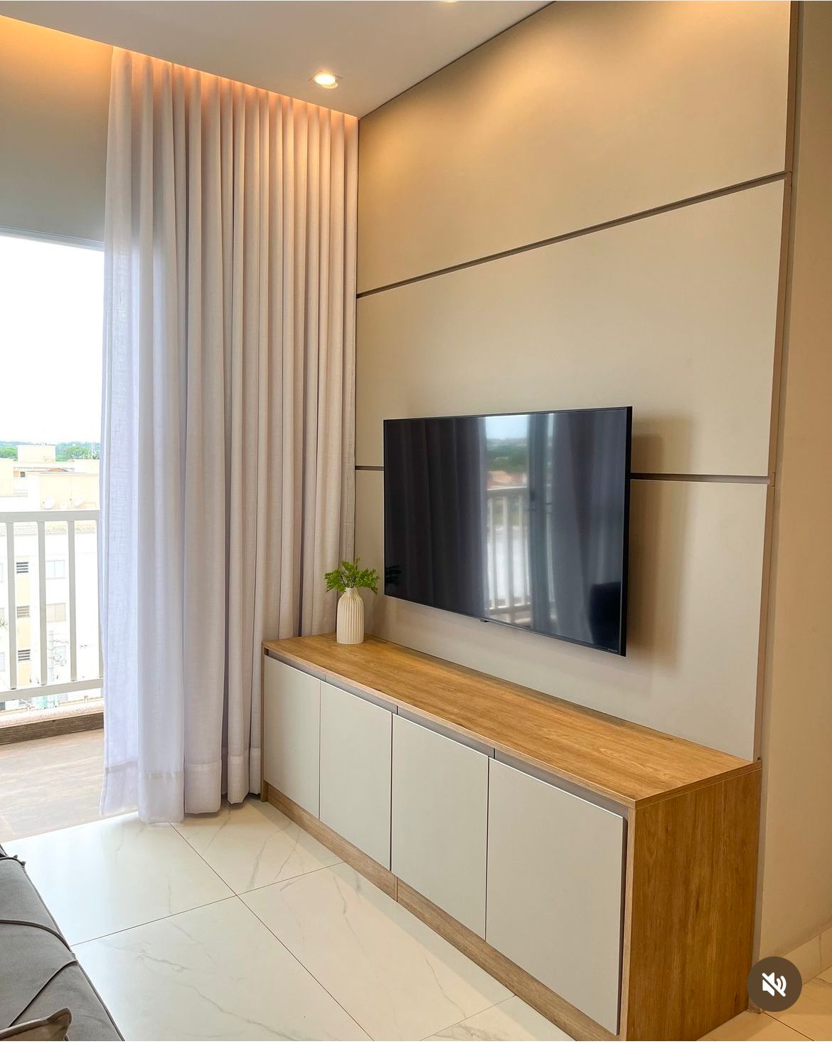 Painel para TV com rack integrado em tons claros com tampo amadeirado em sala de apartamento